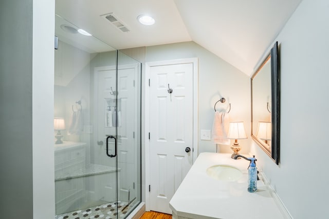 bathroom with vanity, vaulted ceiling, and a shower with door