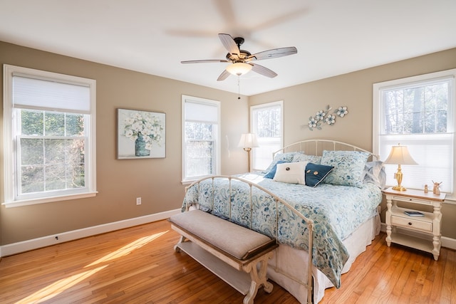 bedroom featuring multiple windows, hardwood / wood-style flooring, and ceiling fan