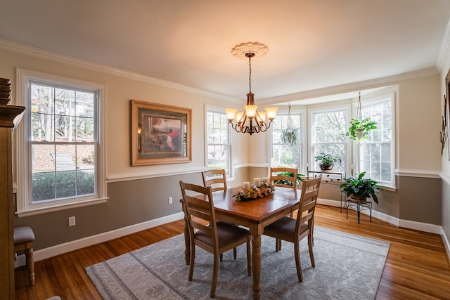 dining area featuring crown molding, dark wood-type flooring, and a chandelier