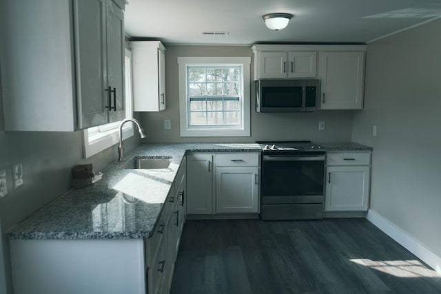 kitchen featuring visible vents, stainless steel appliances, dark wood-style floors, white cabinetry, and a sink