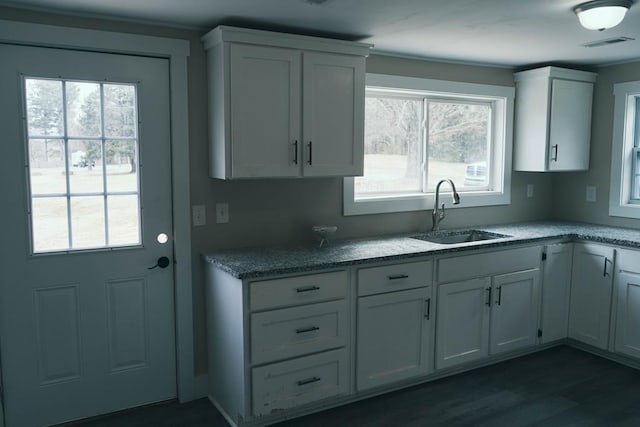 kitchen with plenty of natural light, white cabinets, and a sink