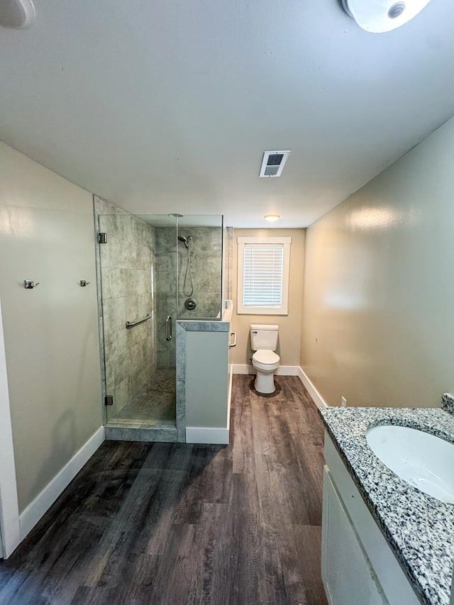 full bathroom with a stall shower, toilet, baseboards, and wood finished floors