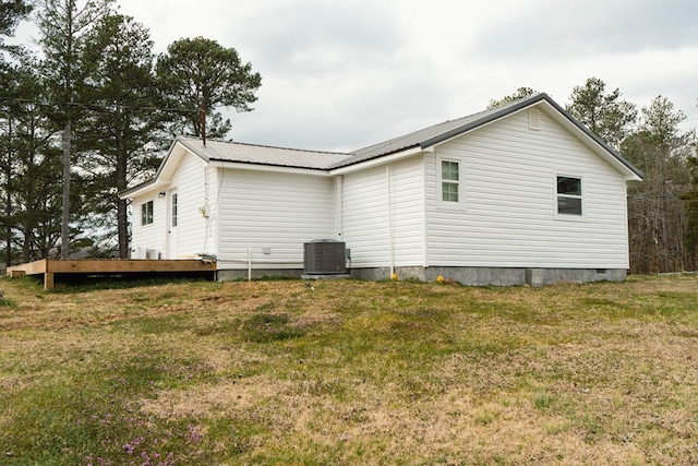 view of property exterior featuring a wooden deck, central AC unit, a lawn, metal roof, and crawl space