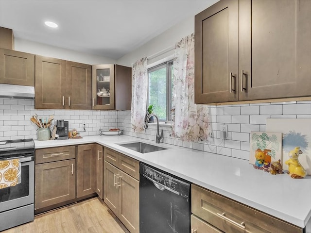 kitchen featuring stainless steel range with electric cooktop, dishwasher, a sink, under cabinet range hood, and light countertops