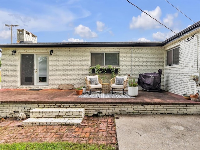 rear view of property with a patio area, brick siding, and a chimney