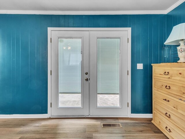 doorway to outside featuring french doors, wood finished floors, baseboards, and crown molding