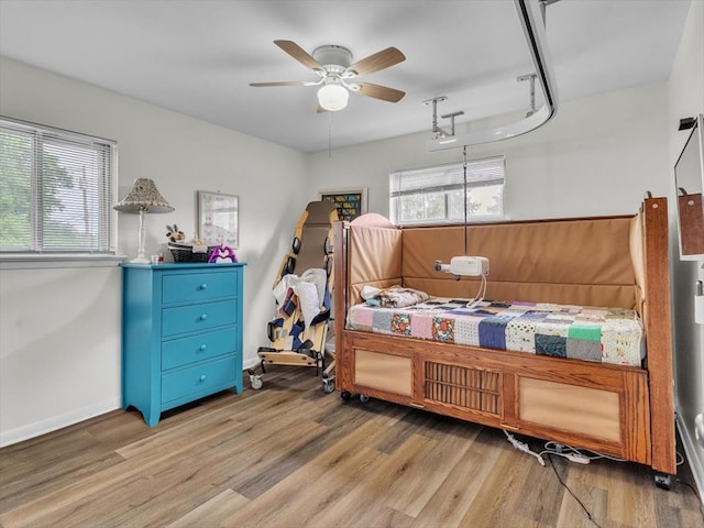 bedroom with light wood-style flooring, ceiling fan, and baseboards