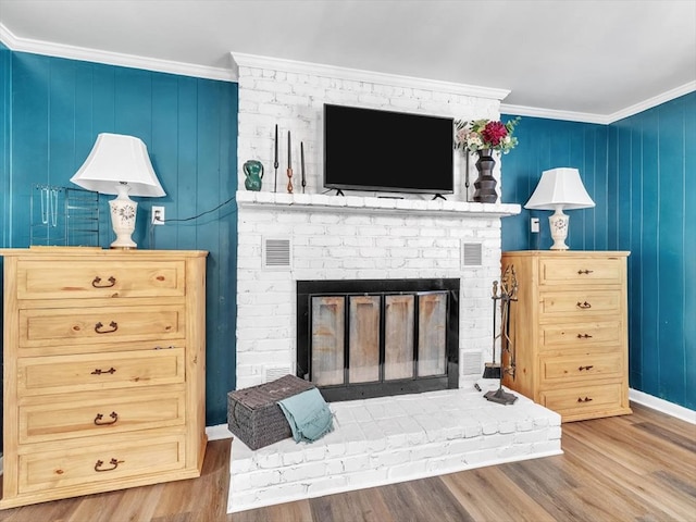 living room featuring wood finished floors, ornamental molding, a brick fireplace, and baseboards
