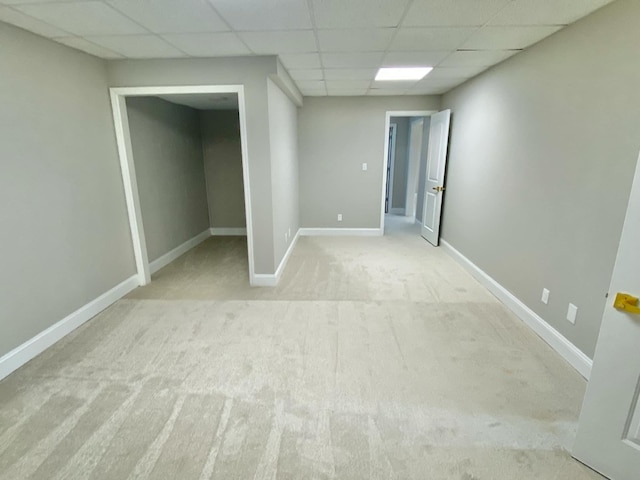 basement with a drop ceiling and light carpet