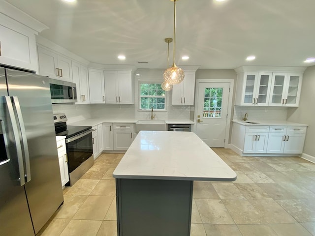 kitchen featuring sink, white cabinetry, a center island, hanging light fixtures, and appliances with stainless steel finishes