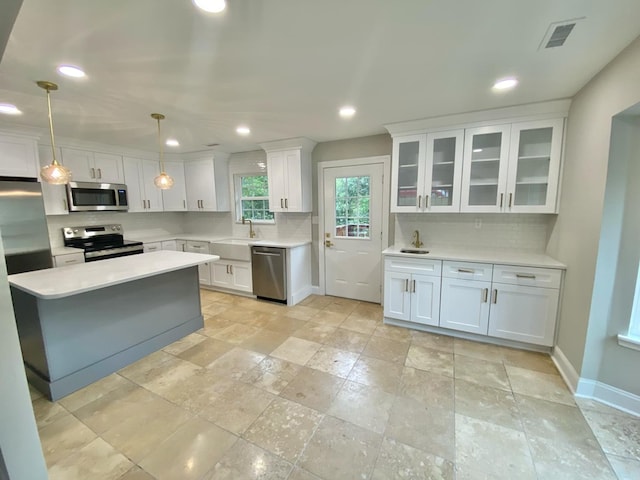 kitchen featuring white cabinetry, decorative backsplash, stainless steel appliances, and hanging light fixtures