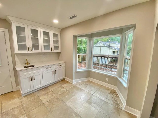 interior space featuring sink, decorative backsplash, and white cabinets