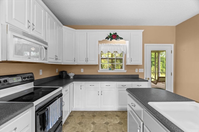 188 Valley Rd, Chatsworth, GA 30705 - kitchen featuring black range with electric cooktop, white microwave, white cabinetry, dark countertops, and a textured ceiling