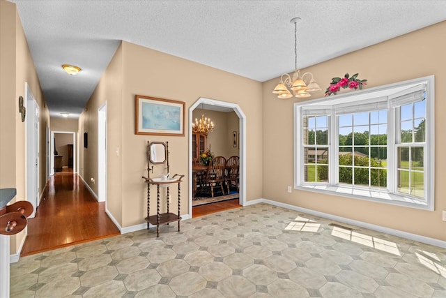 188 Valley Rd, Chatsworth, GA 30705 - unfurnished dining area with a chandelier, a textured ceiling, and arched walkways