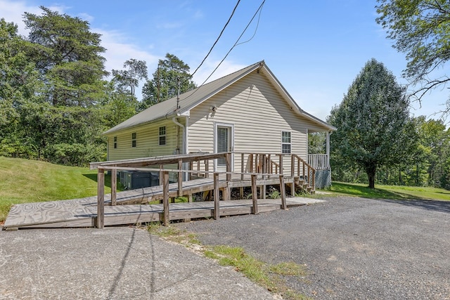 rear view of house featuring a deck and a lawn