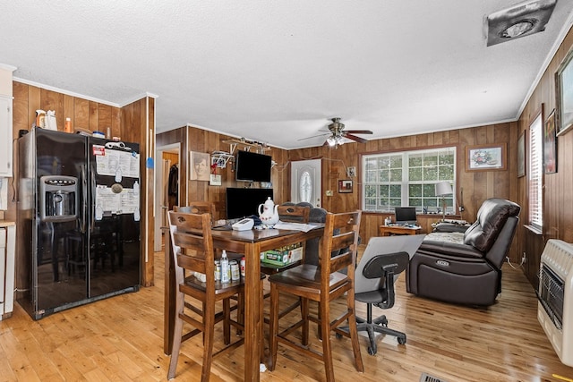 dining area featuring ornamental molding, heating unit, a textured ceiling, and light hardwood / wood-style floors