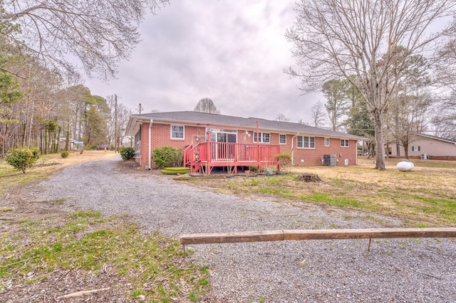 ranch-style house featuring a wooden deck, central air condition unit, and brick siding