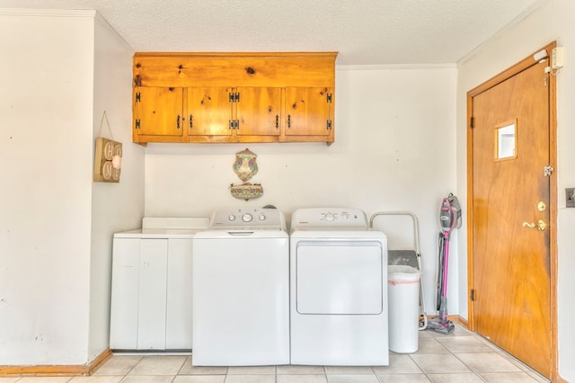 laundry room with light tile patterned floors, washing machine and clothes dryer, cabinet space, a textured ceiling, and crown molding