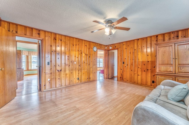 living room with baseboards, light wood-style floors, a ceiling fan, and a textured ceiling