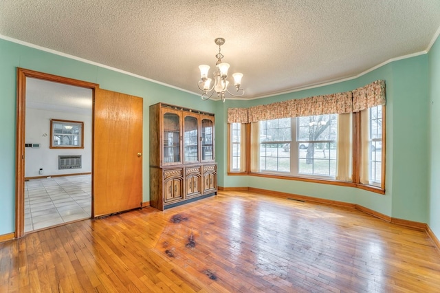 spare room with a notable chandelier, crown molding, visible vents, and hardwood / wood-style floors