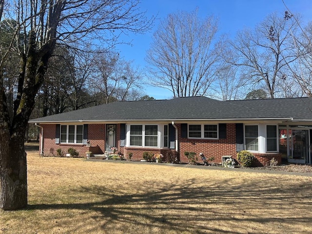 single story home with brick siding, a front lawn, and a shingled roof