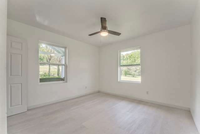 empty room with light wood-style flooring, baseboards, a wealth of natural light, and ceiling fan