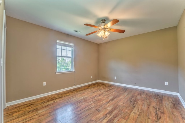 unfurnished room featuring wood finished floors, visible vents, baseboards, and ceiling fan