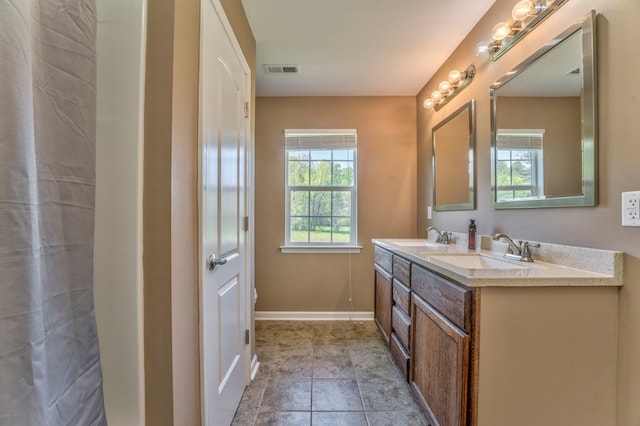 full bath with double vanity, visible vents, baseboards, and a sink