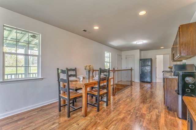 dining space with baseboards, wood finished floors, visible vents, and recessed lighting