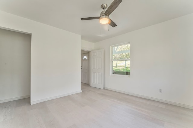 spare room featuring light wood finished floors, baseboards, and ceiling fan