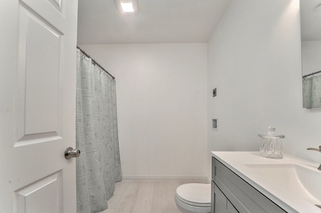 full bathroom with toilet, vanity, wood finished floors, and baseboards