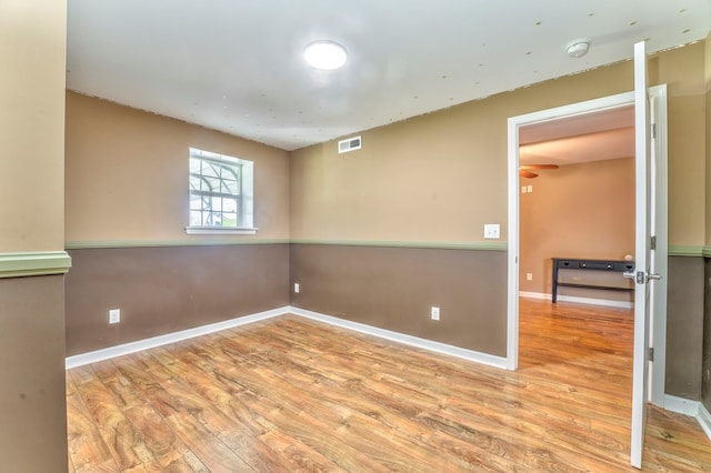 empty room with baseboards, wood finished floors, and visible vents