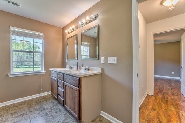 bathroom with double vanity, visible vents, baseboards, and a sink