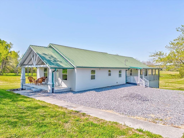 view of front of house featuring metal roof, driveway, a front yard, and covered porch