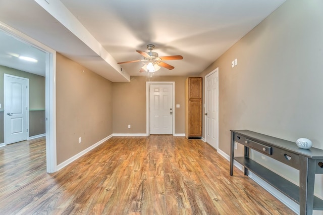 spare room featuring ceiling fan, baseboards, and light wood-type flooring