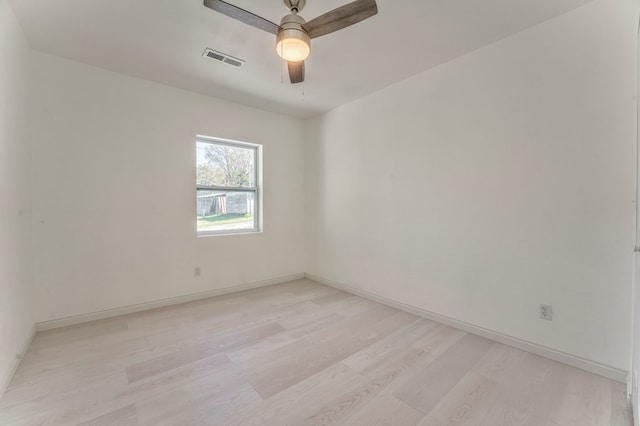 empty room with light wood finished floors, baseboards, a ceiling fan, and visible vents