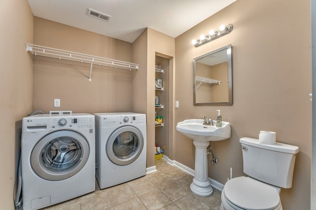 washroom featuring washing machine and dryer, baseboards, visible vents, tile patterned flooring, and laundry area