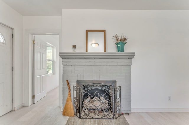 details featuring baseboards, a brick fireplace, and wood finished floors
