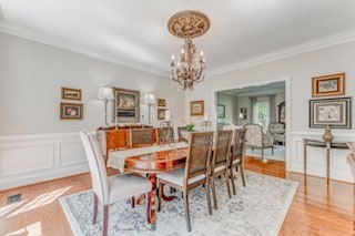 1603 Habersham Way, Dalton, GA 30720 - dining room featuring crown molding, a chandelier, a decorative wall, a wainscoted wall, and wood finished floors