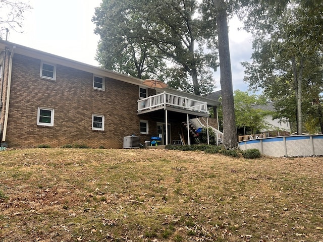 rear view of property featuring a pool side deck, a yard, and central air condition unit