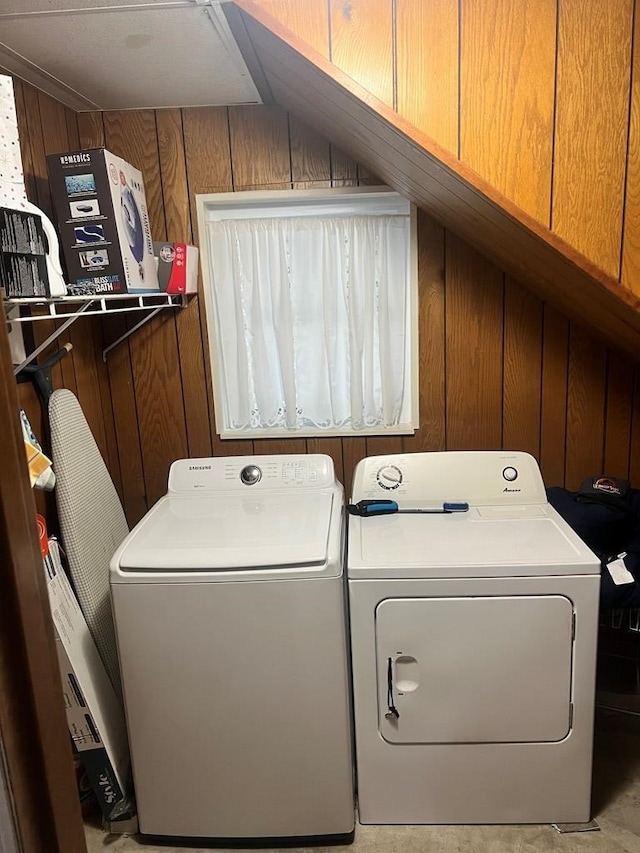 laundry area featuring wooden walls and separate washer and dryer