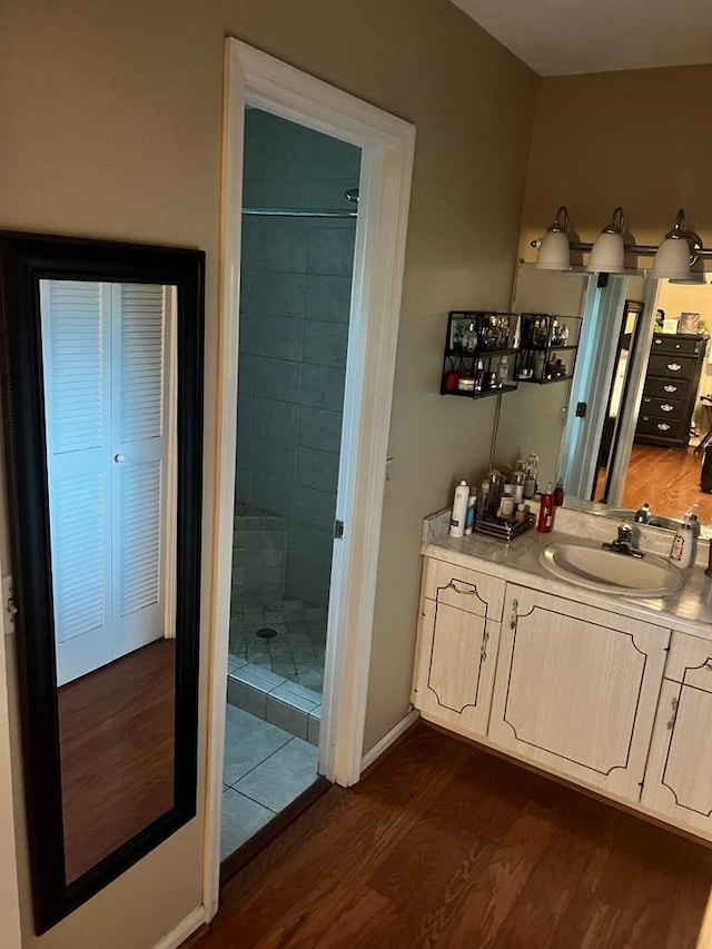 bathroom with vanity, wood-type flooring, and tiled shower