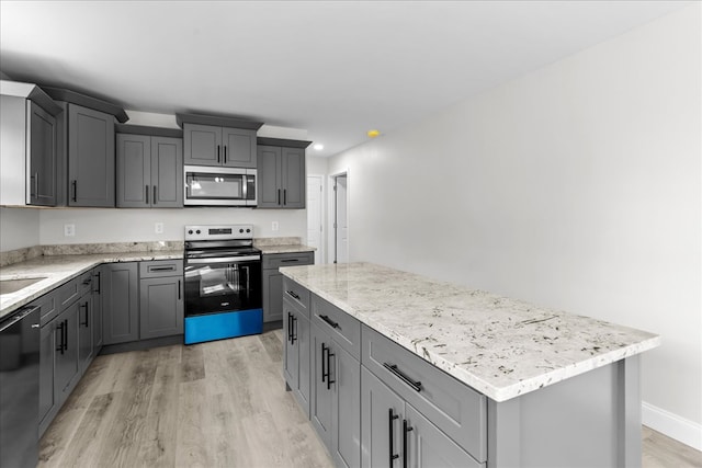 519 Abigail St, Dalton, GA 30721 - kitchen with appliances with stainless steel finishes, gray cabinets, light wood-type flooring, a kitchen island, and light stone countertops