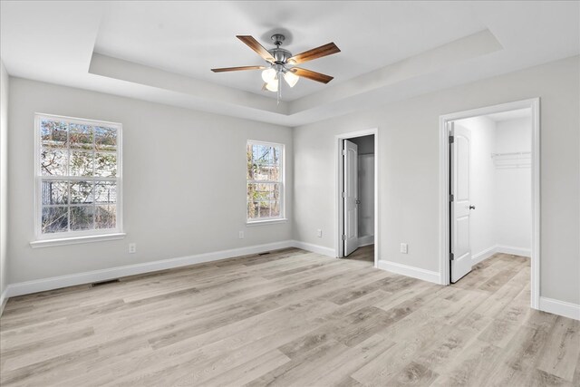 519 Abigail St, Dalton, GA 30721 - unfurnished bedroom with a tray ceiling, a walk in closet, light wood-type flooring, baseboards, and a closet