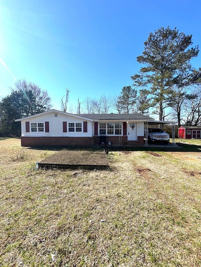 single story home with brick siding, a carport, and a front yard