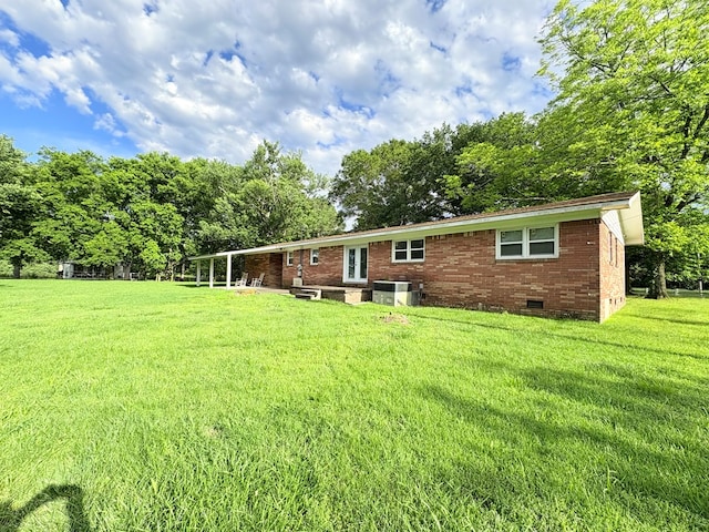 back of house featuring crawl space, a yard, brick siding, and central air condition unit
