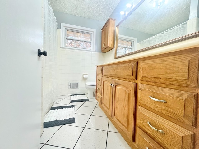 bathroom featuring tile walls, tile patterned flooring, vanity, a textured ceiling, and toilet