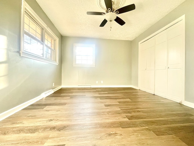 unfurnished bedroom with hardwood / wood-style floors, a closet, a textured ceiling, and ceiling fan