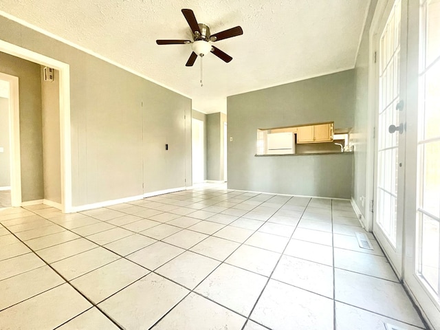 empty room with ceiling fan, a textured ceiling, and light tile patterned floors