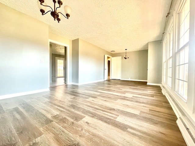 unfurnished room featuring hardwood / wood-style flooring, a textured ceiling, and a chandelier